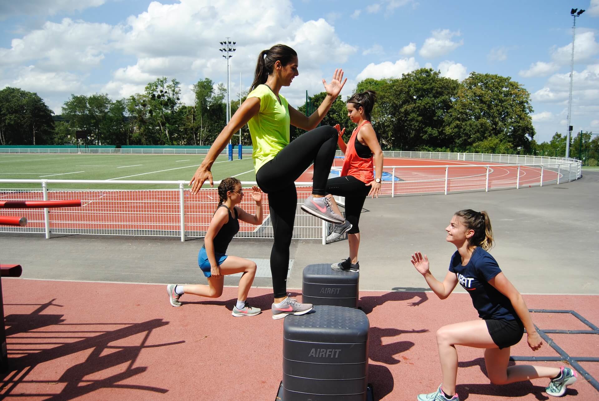 4 amigas haciendo ejercicios cardiovasculares en un estadio